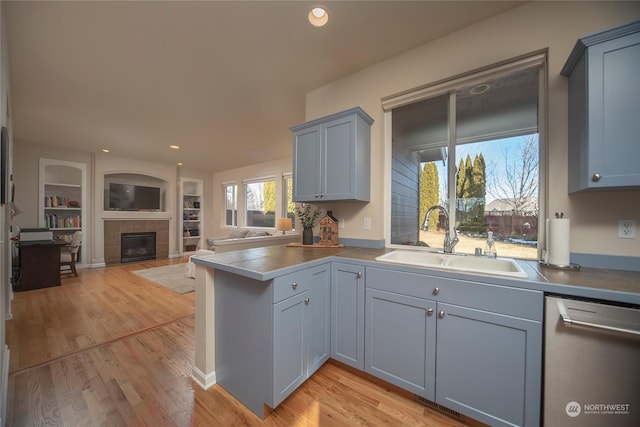 kitchen featuring built in shelves, dishwasher, sink, and light hardwood / wood-style flooring