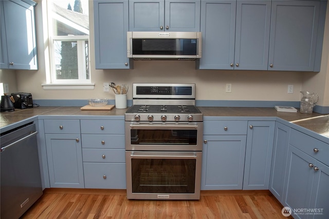 kitchen featuring light wood-style floors, tile counters, and stainless steel appliances