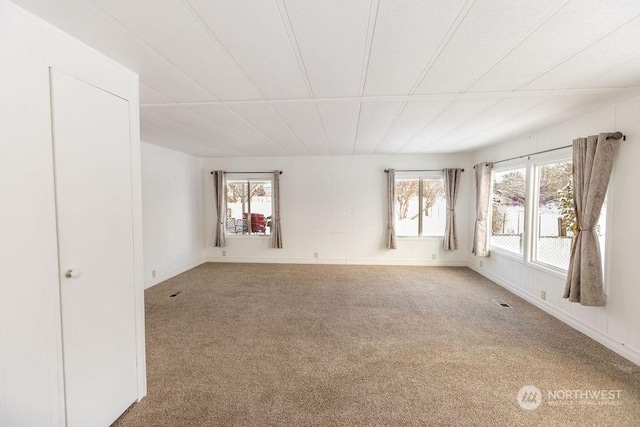 spare room with carpet, visible vents, and baseboards