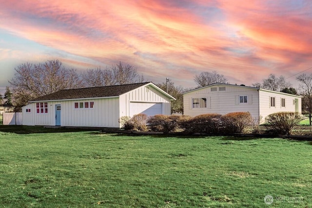 property exterior at dusk with a garage, a yard, and an outdoor structure