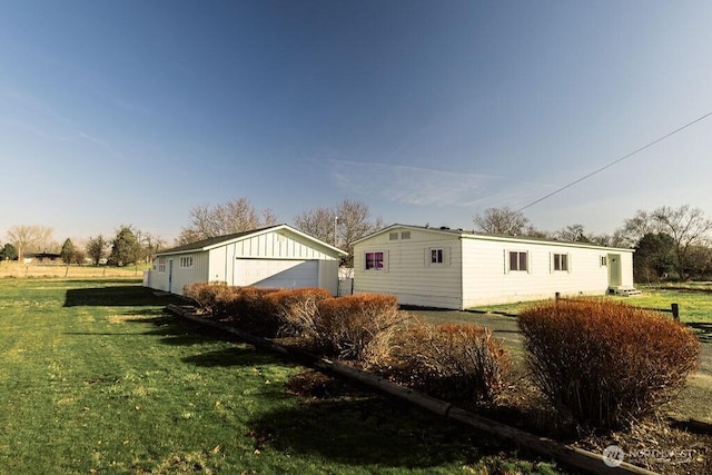 exterior space featuring a garage, an outbuilding, and a lawn