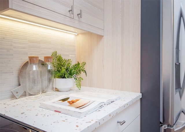 kitchen featuring light stone countertops and stainless steel refrigerator