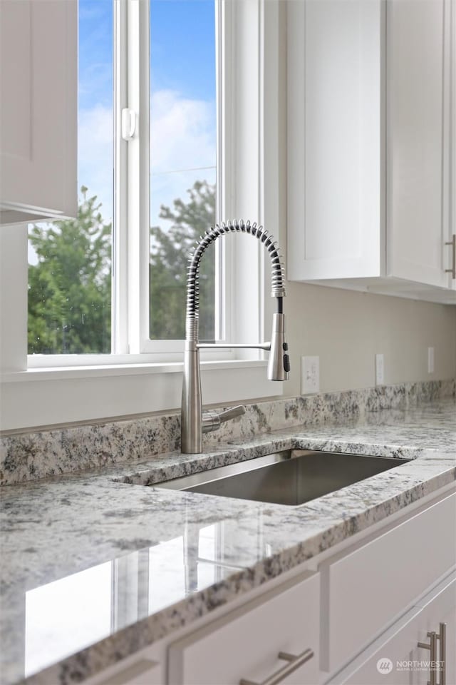 kitchen featuring light stone counters and white cabinets