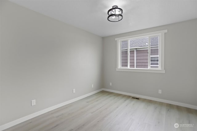 spare room featuring wood finished floors, visible vents, and baseboards