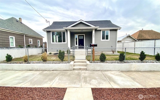 bungalow with a gate, a fenced front yard, and a shingled roof