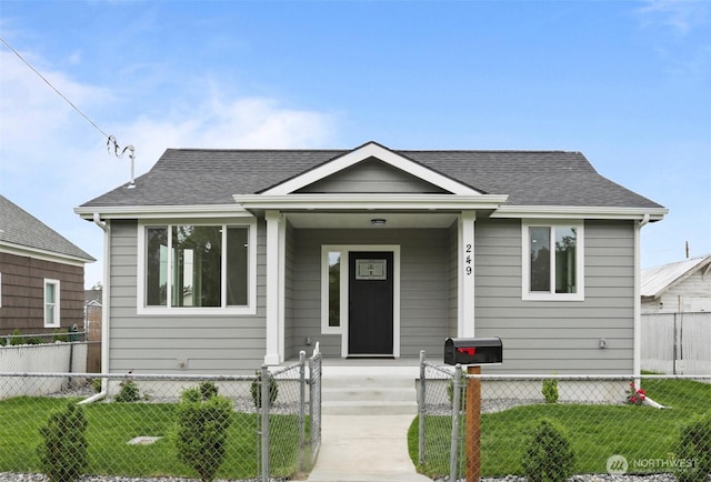 bungalow-style house featuring a front lawn, covered porch, a fenced front yard, and roof with shingles