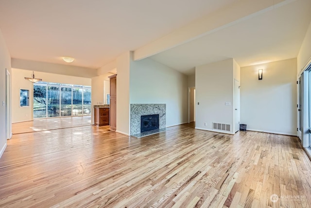 unfurnished living room with light hardwood / wood-style floors and vaulted ceiling with beams