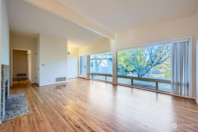 unfurnished living room with light hardwood / wood-style floors and beam ceiling