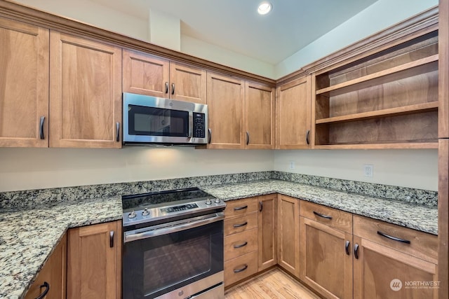 kitchen with light stone counters, light hardwood / wood-style floors, and stainless steel appliances