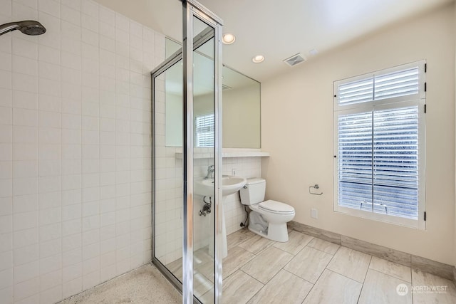 bathroom with a tile shower, toilet, and tile patterned floors