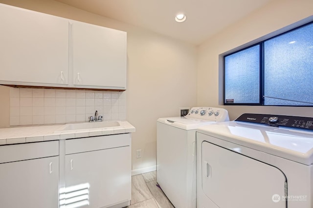 washroom with cabinets, separate washer and dryer, and sink