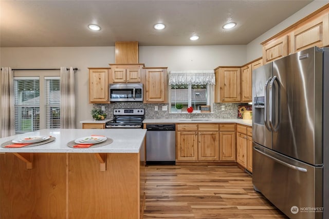 kitchen with light brown cabinetry, tasteful backsplash, sink, a breakfast bar, and stainless steel appliances