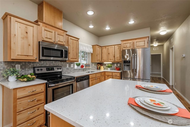 kitchen featuring light stone counters, light brown cabinetry, appliances with stainless steel finishes, and decorative backsplash