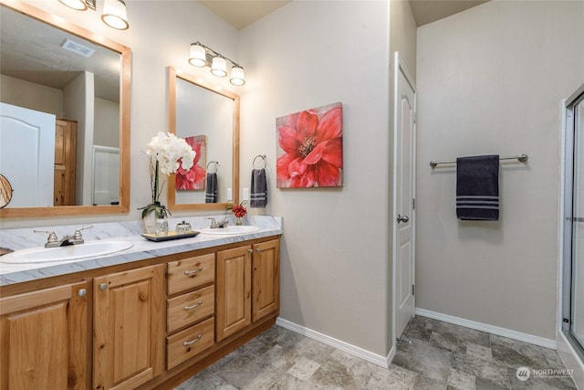 bathroom featuring a shower with shower door and vanity