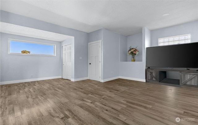 unfurnished living room featuring hardwood / wood-style flooring and a textured ceiling