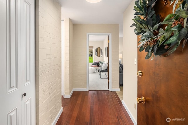 hall with dark hardwood / wood-style floors and brick wall