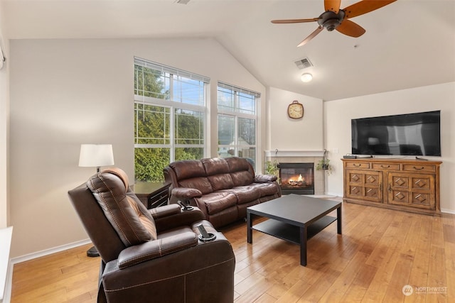 living room with light hardwood / wood-style floors, lofted ceiling, and a tiled fireplace