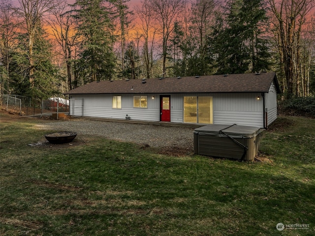 back house at dusk with a lawn