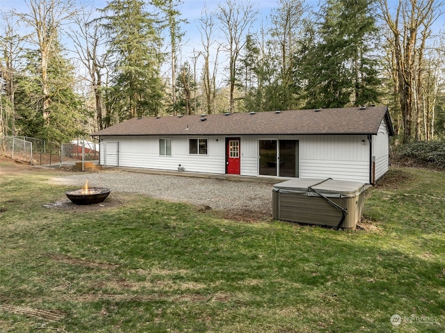 rear view of house with an outdoor fire pit and a yard