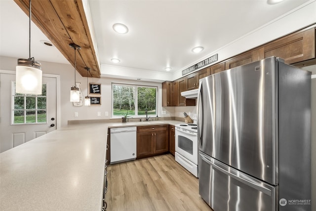 kitchen featuring hanging light fixtures, kitchen peninsula, white appliances, and light hardwood / wood-style floors