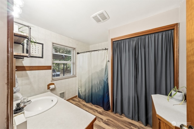 bathroom with vanity, wood-type flooring, and tile walls