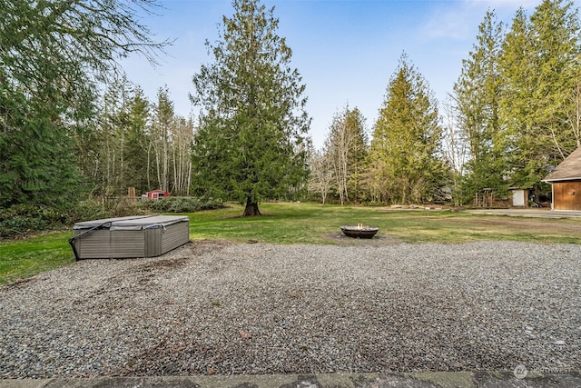 view of yard featuring a hot tub and an outdoor fire pit