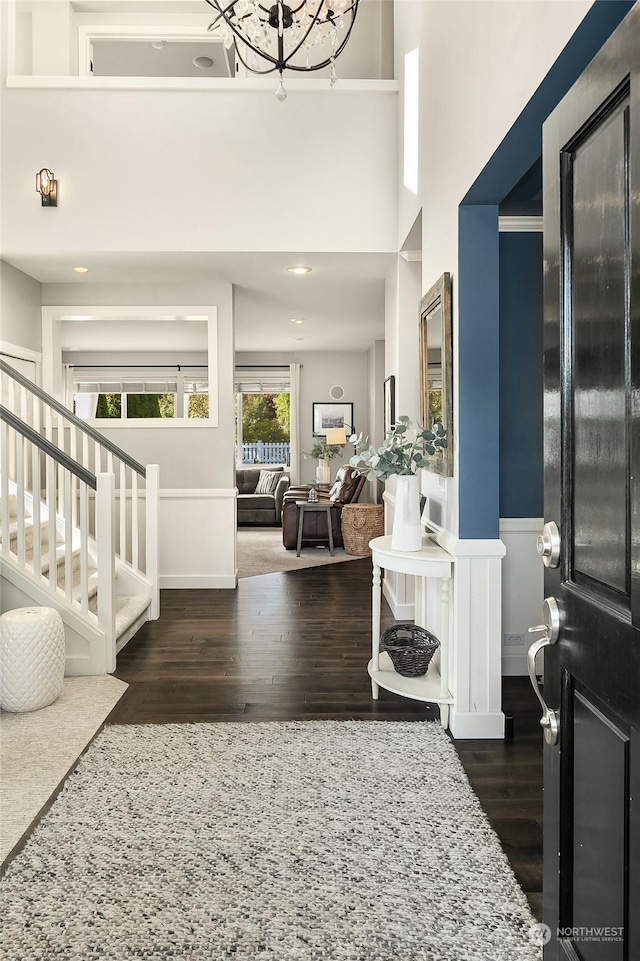 foyer with dark hardwood / wood-style floors, a chandelier, and a towering ceiling