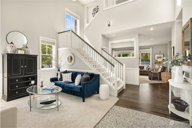 living room featuring dark hardwood / wood-style flooring, a towering ceiling, and a healthy amount of sunlight