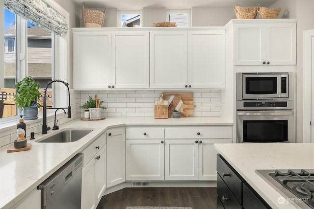 kitchen with sink, white cabinetry, light stone counters, tasteful backsplash, and appliances with stainless steel finishes