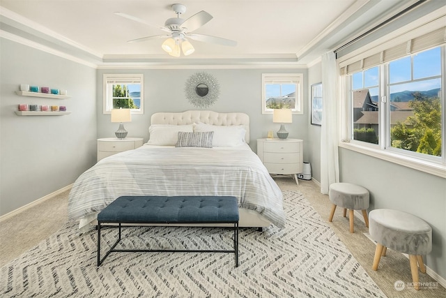 carpeted bedroom featuring a tray ceiling, ornamental molding, and ceiling fan