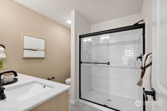 bathroom featuring toilet, tile patterned flooring, walk in shower, and vanity