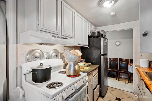 kitchen featuring light tile patterned flooring, wood counters, tasteful backsplash, white cabinetry, and white range