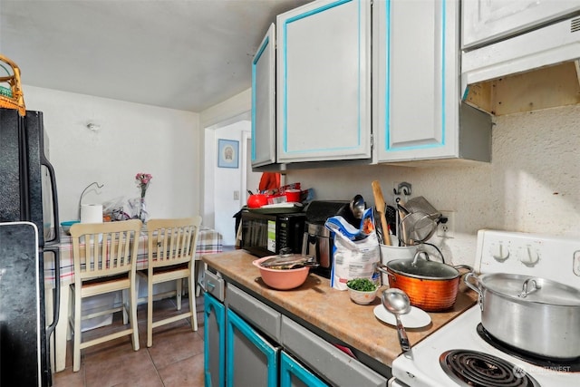 kitchen featuring light tile patterned flooring, black refrigerator, white cabinetry, stove, and blue cabinetry