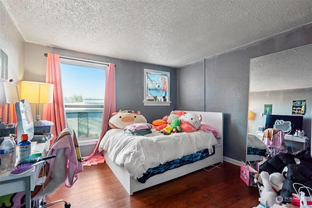 bedroom with multiple windows, dark hardwood / wood-style floors, and a textured ceiling