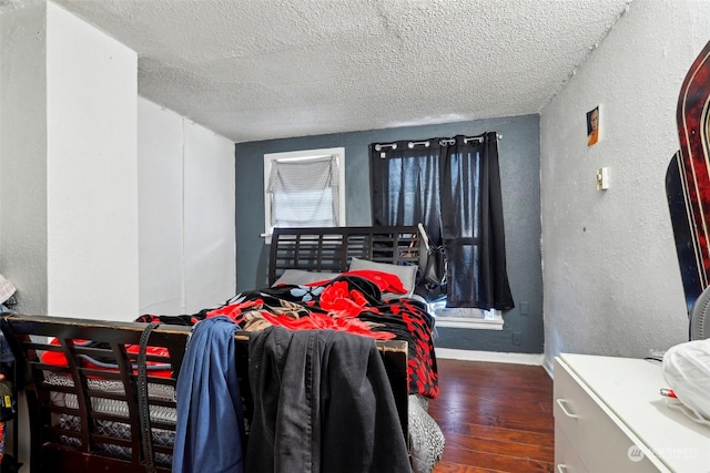 bedroom with dark hardwood / wood-style floors and a textured ceiling