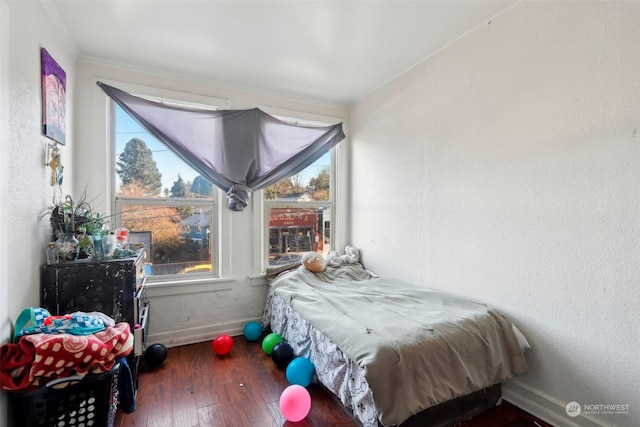 bedroom with ornamental molding and dark hardwood / wood-style floors