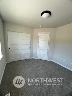 unfurnished bedroom featuring dark carpet and a closet