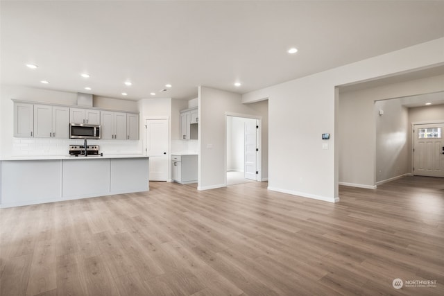 kitchen with backsplash, stainless steel appliances, light hardwood / wood-style floors, and kitchen peninsula