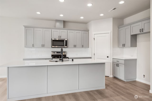 kitchen featuring a kitchen island with sink, sink, gray cabinetry, and appliances with stainless steel finishes