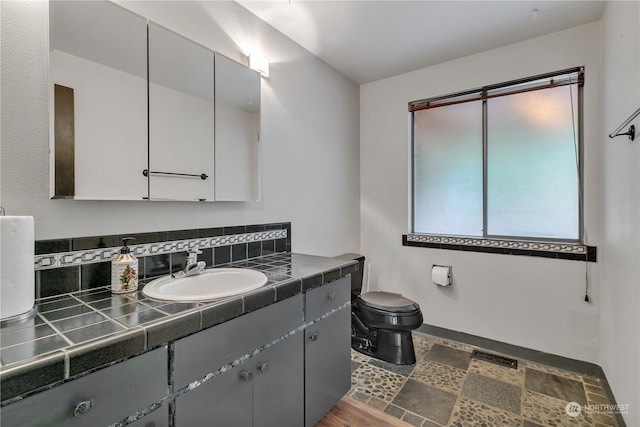 bathroom with vanity, decorative backsplash, and toilet