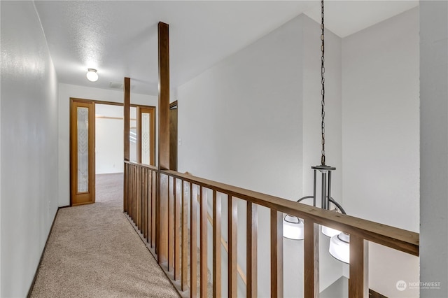 corridor featuring light colored carpet and a textured ceiling