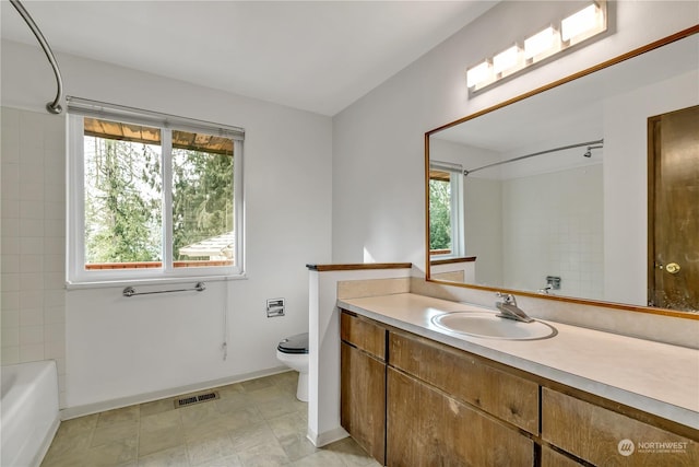 full bathroom with vanity, tiled shower / bath combo, and toilet