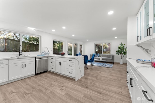 kitchen with light wood-type flooring, dishwasher, sink, and white cabinets