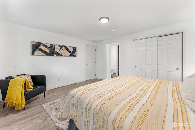 bedroom with ensuite bathroom, light hardwood / wood-style flooring, and a closet