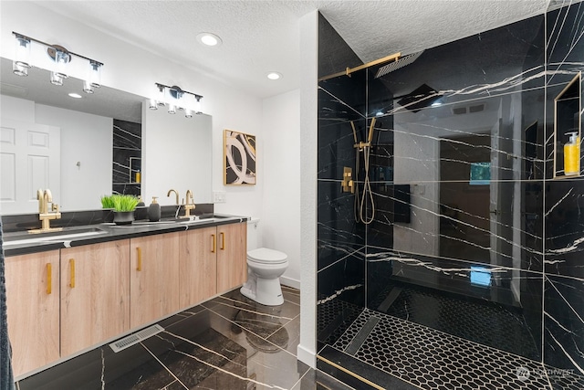 bathroom with vanity, tiled shower, a textured ceiling, and toilet