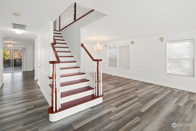 stairs with wood-type flooring, ornamental molding, and a chandelier