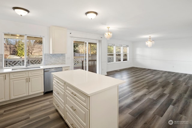 kitchen with stainless steel dishwasher, pendant lighting, sink, backsplash, and a kitchen island