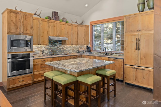 kitchen featuring a center island, sink, a breakfast bar area, stainless steel appliances, and light stone counters