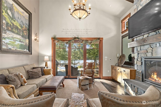 living room featuring a high ceiling, a stone fireplace, and an inviting chandelier