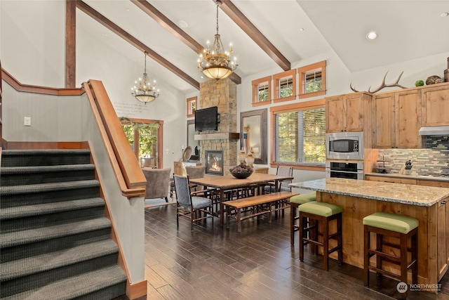 dining area with high vaulted ceiling, beam ceiling, a chandelier, and a fireplace